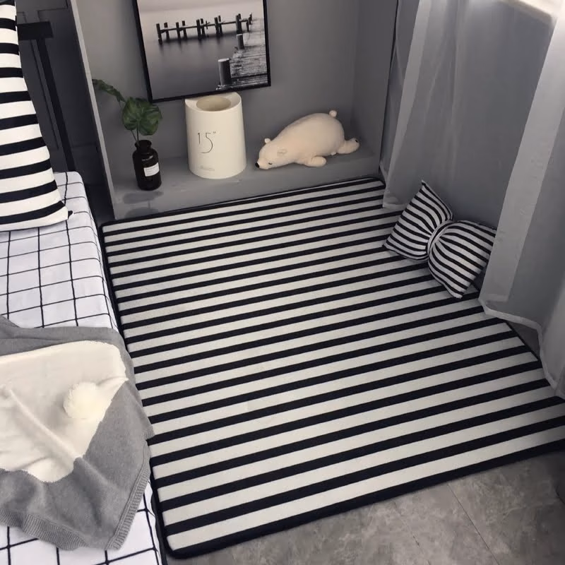 A black and white striped graphic carpet next to the bed to wake up the room