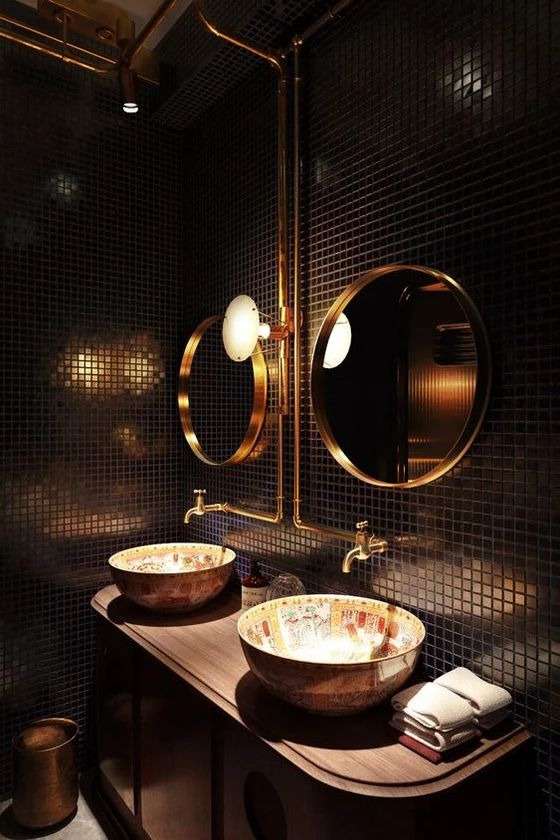 glossy black tiles adorned with gleaming chrome fittings and a majestic gold-framed mirror.